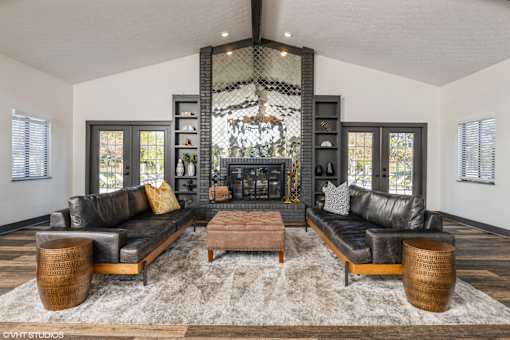 A living room with a black leather couch, a wooden coffee table, and a chandelier at Karric Place of Dublin Apartments, Dublin, 43016