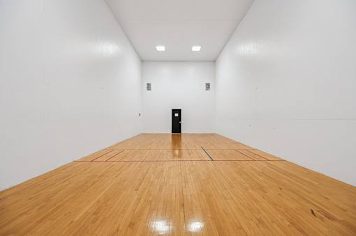 A black object is placed in the middle of a room with wooden flooring.