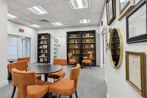 A room with a table surrounded by chairs and bookshelves.
