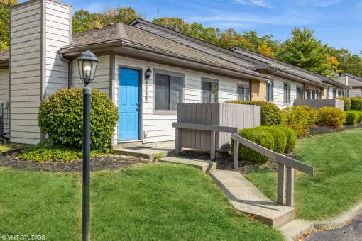 a house with a blue door and a wooden bench in front of it at Silvertree at Little Turtle Apartments, Westerville