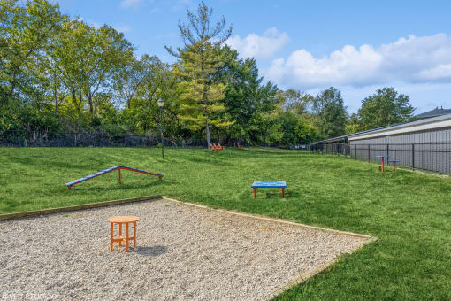 a fenced in backyard with a grassy field and a playground with a bench at Runaway Bay Apartments, Columbus, 43204