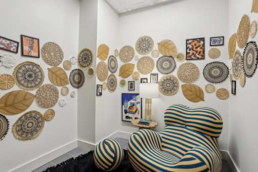 A chair with a black and gold striped cover sits in front of a wall with circular and leaf shaped decorations.