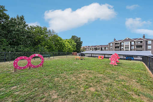 A grassy area with a pink sculpture and a building in the background.