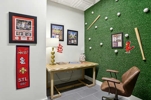 A room with a green wall and a wooden desk with a chair.