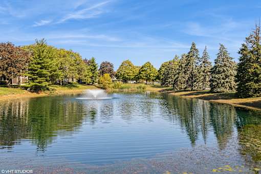 A serene lake surrounded by trees under a clear blue sky at Island Club Apartments, Columbus, 43235