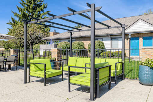 A patio with green chairs and a black metal pergola at Karric Place of Dublin Apartments, Dublin, OH
