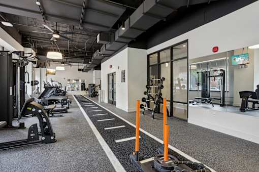 A gym with a variety of equipment including treadmills, weights, and exercise machines.