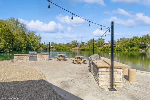 a patio with a grill and picnic table overlooking the water at Runaway Bay Apartments, Columbus, Ohio