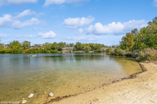 a lake with a sandy beach and trees at Runaway Bay Apartments, Columbus, OH, 43204