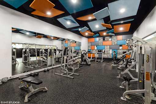 A gym with a variety of equipment including a squat rack, a bench press, and a leg press at Island Club Apartments, Columbus, 43235