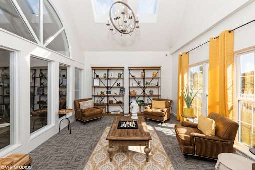 A living room with a brown sofa, a wooden coffee table, and a chandelier at Island Club Apartments, Ohio, 43235