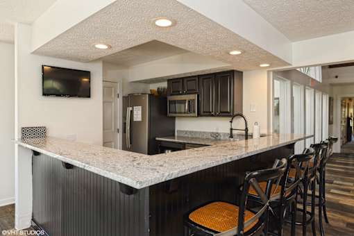 A kitchen with a bar area and a television mounted on the wall. at Island Club Apartments, Columbus, OH