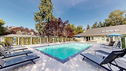 A swimming pool surrounded by lounge chairs and trees.
