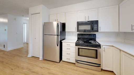 A kitchen with a refrigerator, oven, and microwave.