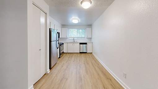 A kitchen with a refrigerator, sink, and trash can.