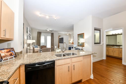 a kitchen with granite countertops and wooden cabinets with a living room in the background at Bristol On Union Apartment Homes, Memphis, TN, 38104