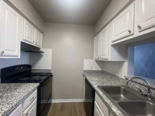 a kitchen with granite counter tops and white cabinets at Whispering Oaks, Texas, 77301