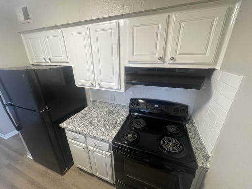 a kitchen with white cabinets and black stove and refrigerator at Whispering Oaks, Conroe, TX ? 