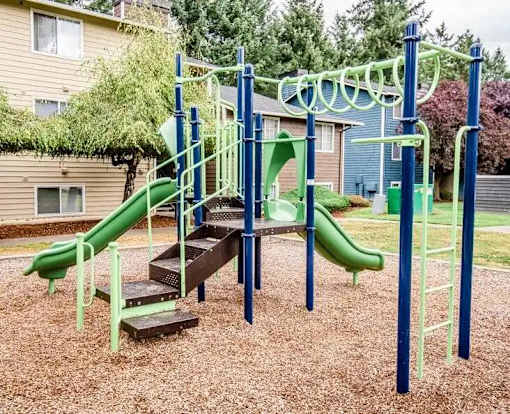 A playground with a green slide and a wooden platform at Ellyson Apartment Homes, Washington, 98444
