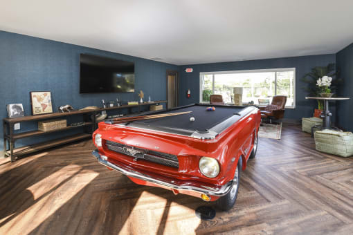 a pool table and tv in a living room with a red car in the middle of the