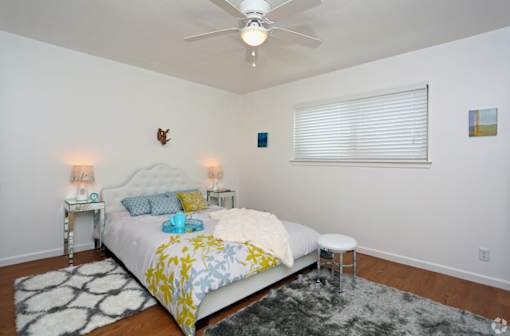 A bedroom with a bed, two lamps, and a rug.