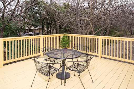 A table and chairs set on a wooden deck.