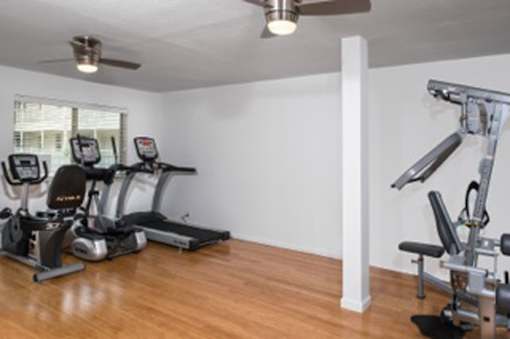 A gym room with a treadmill, elliptical trainer and a weight machine.