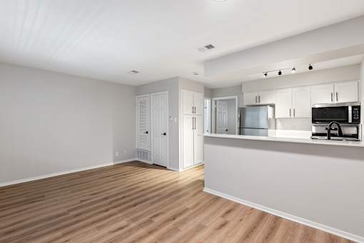 A kitchen with white cabinets and a wooden floor.