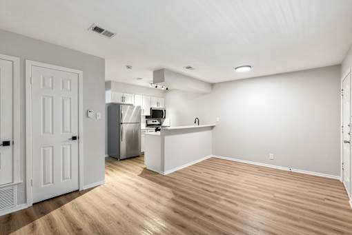 A kitchen with white cabinets and a wooden floor.