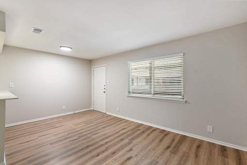 A room with wooden flooring and a window with blinds.