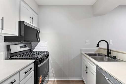 A kitchen with white cabinets and black appliances.