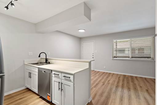A kitchen with white cabinets and a wooden floor.