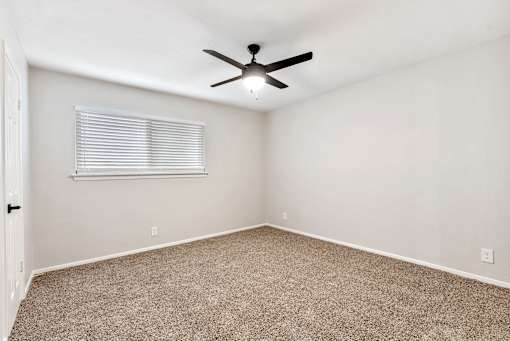 A room with a ceiling fan and carpeted floor.