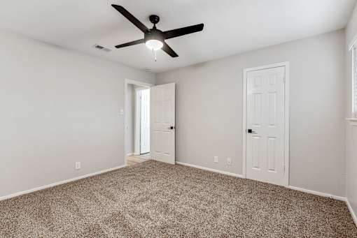 A room with a ceiling fan and carpeted floor.