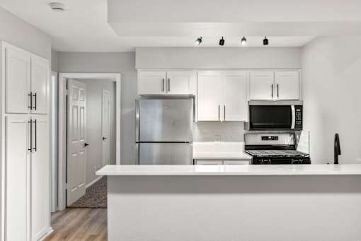 A modern kitchen with white cabinets and appliances.