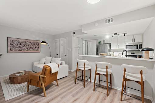 A modern kitchen with white cabinets and a white island with bar stools.
