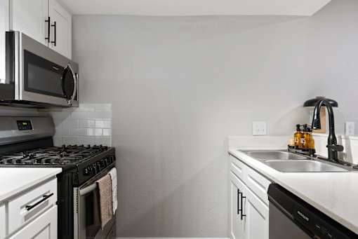 A modern kitchen with a black stove top and white cabinets.