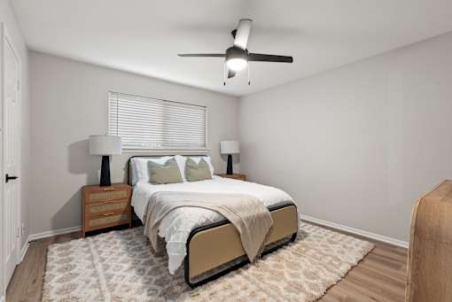 A bedroom with a bed, two lamps, and a ceiling fan.