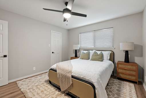 A bedroom with a bed, nightstand, and ceiling fan.