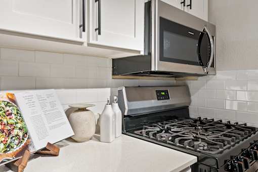 A modern kitchen with a stove, microwave, and white cabinets.