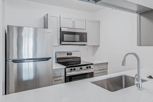 A modern kitchen with a stainless steel refrigerator, oven, and microwave at Water Ridge Apartments , Texas