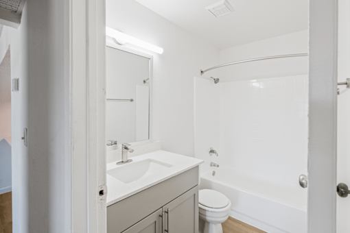 A white bathroom with a toilet, sink, and bathtub at Water Ridge Apartments , Irving, Texas
