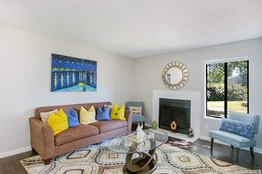 A living room with a brown couch, a coffee table, and a painting on the wall at Water Ridge Apartments , Irving, 75061