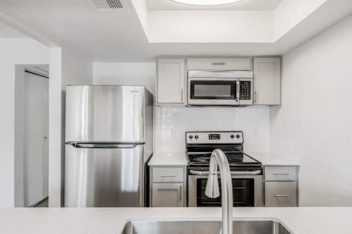 A modern kitchen with stainless steel appliances and white cabinets at Water Ridge Apartments , Irving, 75061
