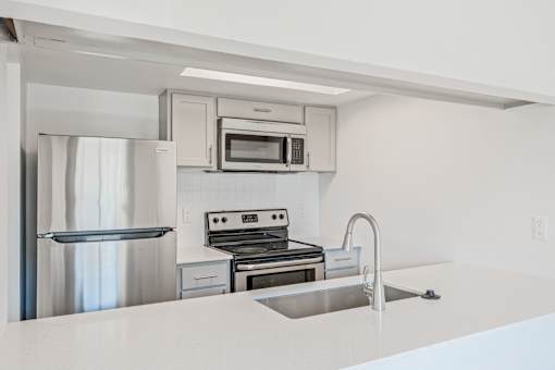 A modern kitchen with stainless steel appliances and white countertops at Water Ridge Apartments , Irving, TX