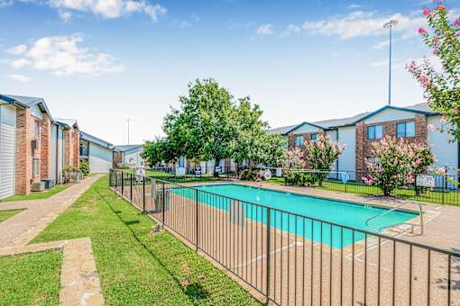 A pool surrounded by a fence in a sunny day at Water Ridge Apartments , Texas, 75061