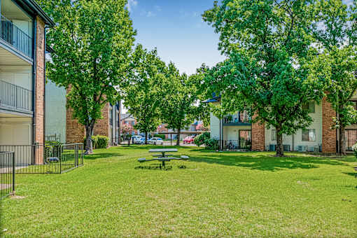 A park with a picnic table surrounded by trees and buildings at Water Ridge Apartments , Irving, Texas