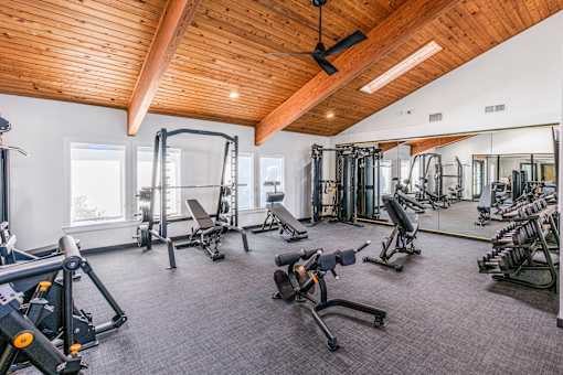 A gym with a variety of equipment including weights and machines at Water Ridge Apartments , Irving