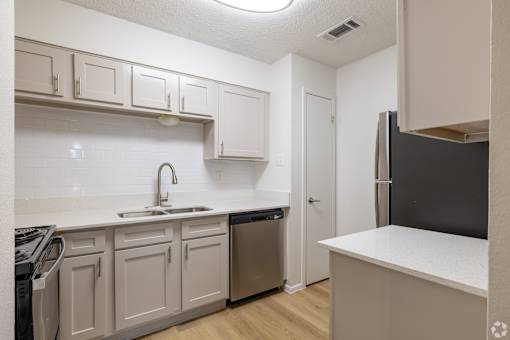 A kitchen with white cabinets and a black refrigerator.