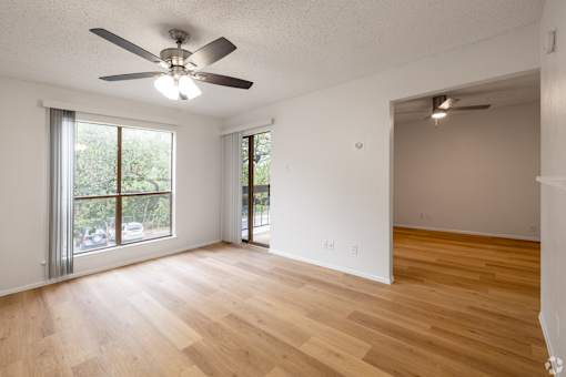 A room with a ceiling fan and wooden flooring.